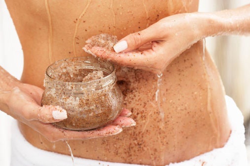 Woman applying scrub to abdomen, mid section, close-up
