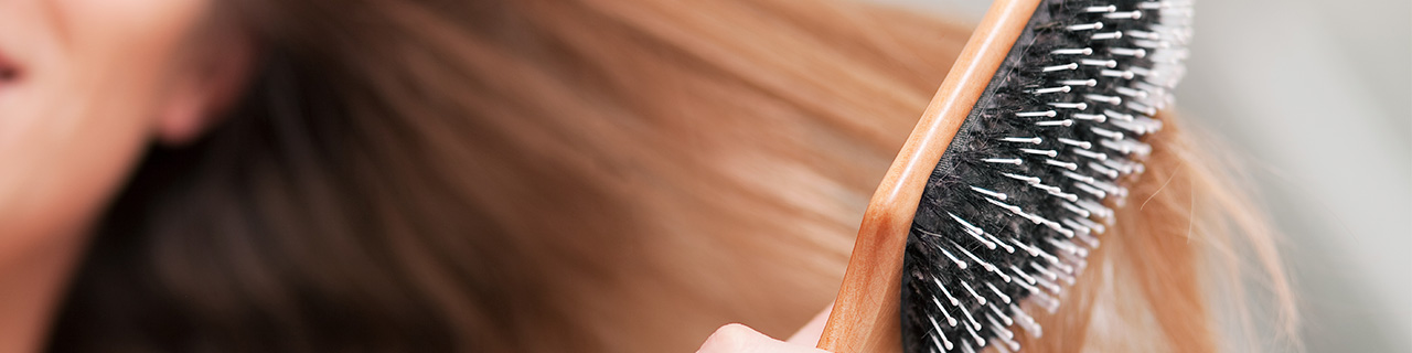 Mulher escovando seu cabelo forte e saudável depois de colocar as dicas que encontrou sobre o que é bom para caspa em prática