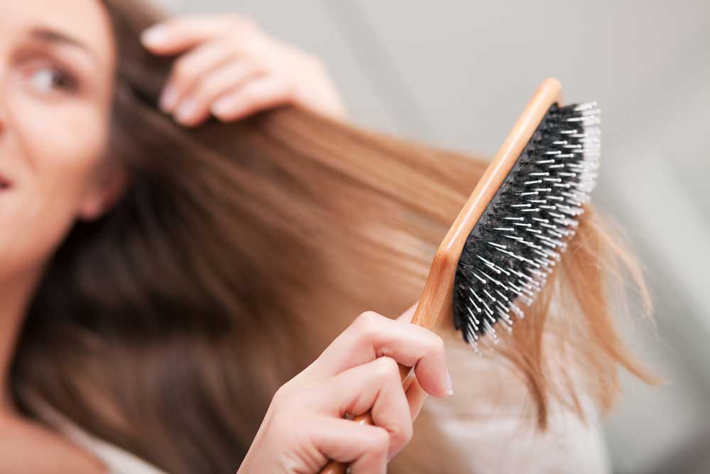 Mulher com dermatite seborreica penteando o cabelo