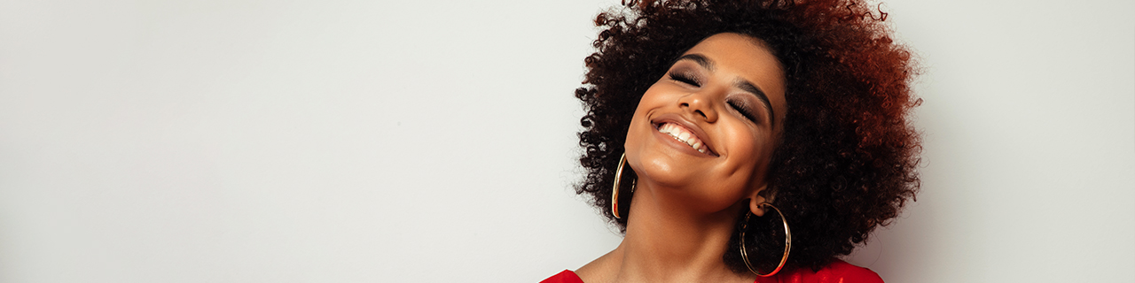 Mulher com cabelo bem definido, sorridente e feliz após aplicar técnica de finalização para cabelo cacheado tipo 3b.