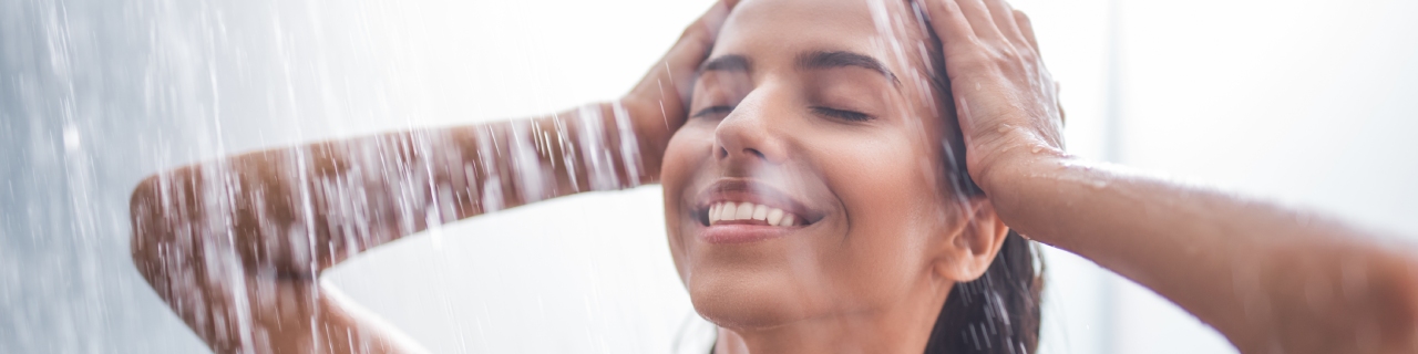 Mulher no chuveiro com expressão de relaxamento enquanto aproveita os benefícios do banho premium.