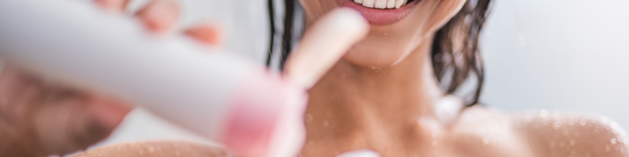Mulher sorrindo ao tomar banho e aplicar um sabonete líquido cheiroso da Palmolive na esponja